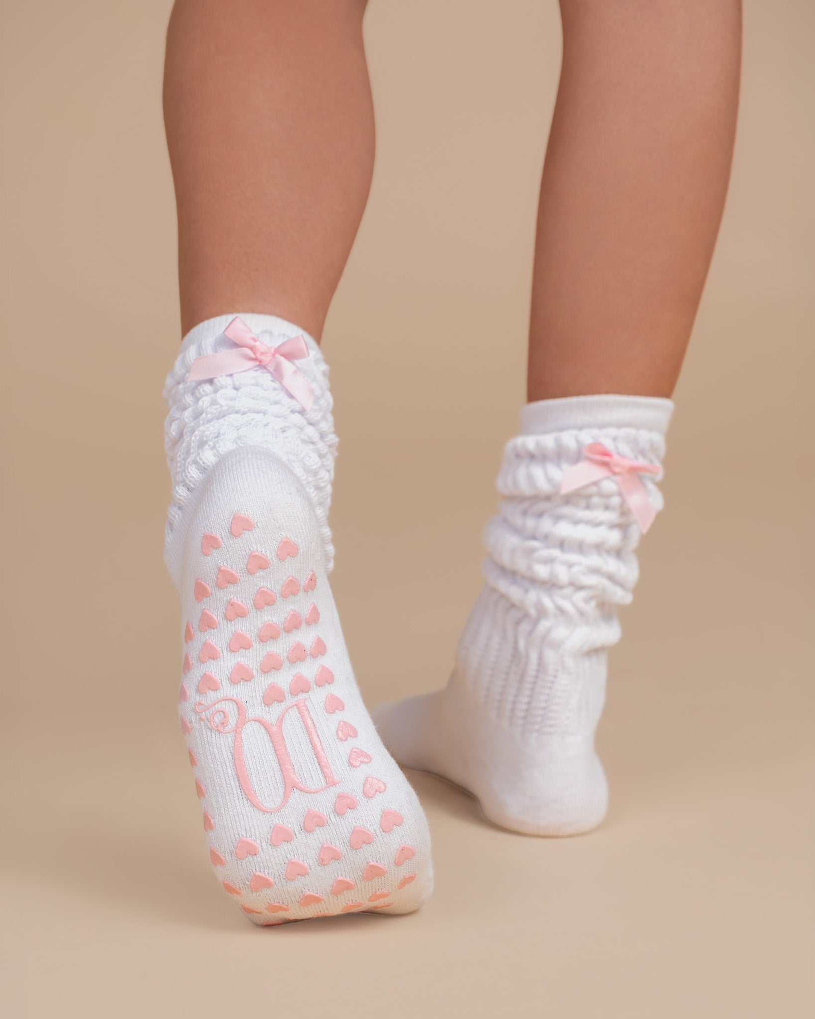 White grip pilates bed socks with pink hearts, logo and pink bow