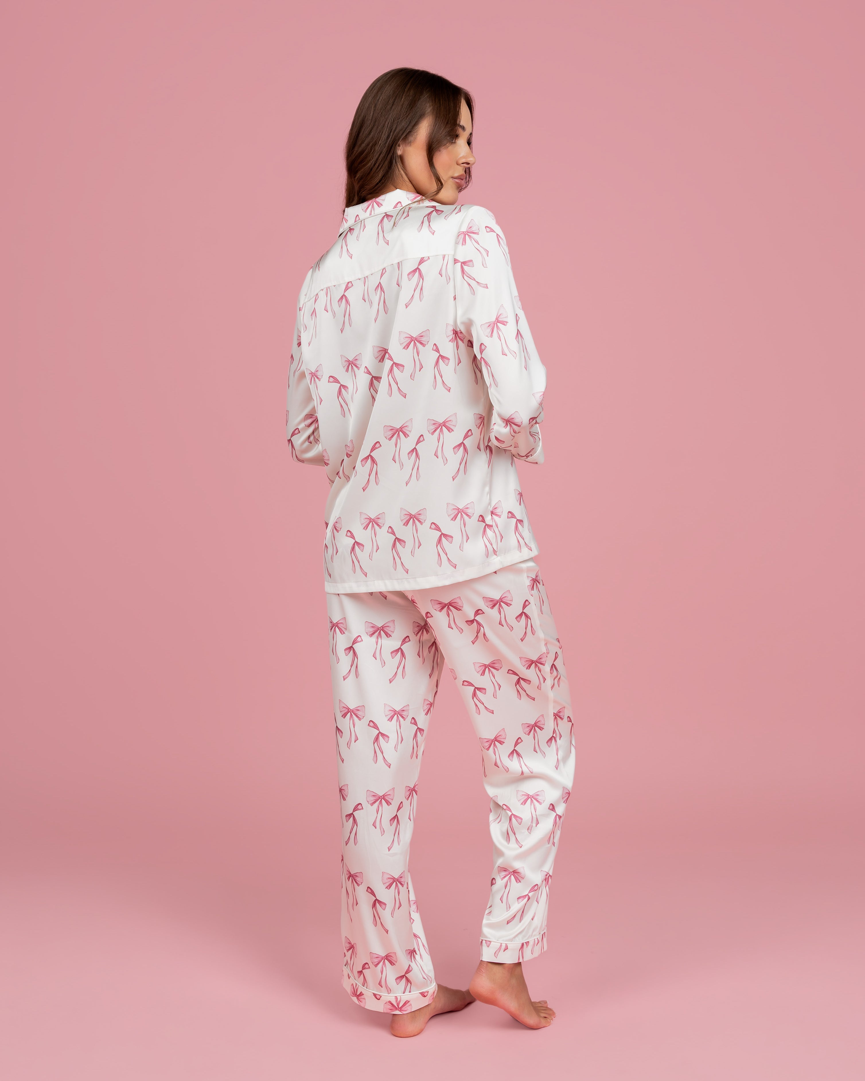 Model wearing Dream Queen Co. Sleep Cute Long sleeve satin set in Coquette Code pink Bow Print