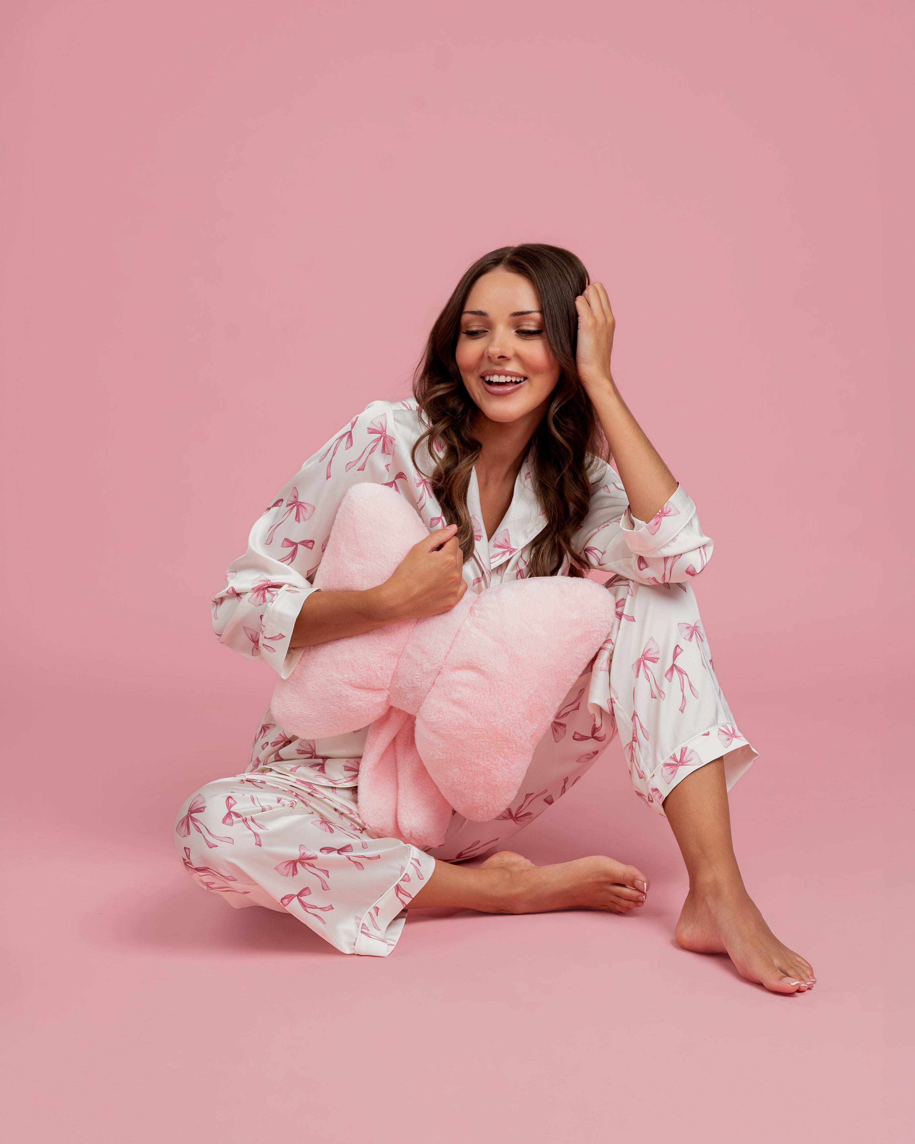 Model wearing Dream Queen Co. Sleep Cute Long sleeve satin PJ set in Coquette Code pink Bow Print