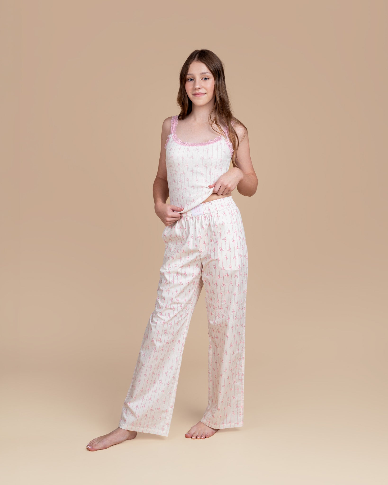 Teen model wearing Dream Queen Co. Love Lines waffle top in pink bow stripe, and love lines pink bow stripe lounge pant