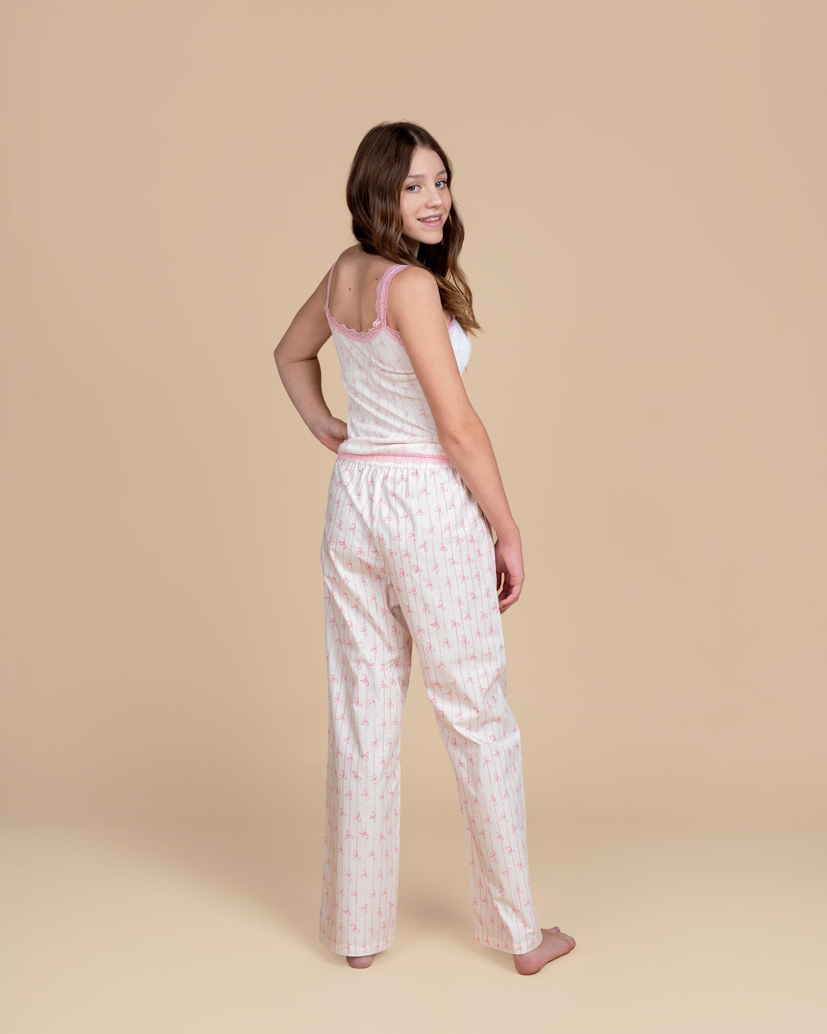 Teen model wearing Dream Queen Co. Love Lines waffle top in pink bow stripe, and love lines pink bow stripe lounge pant