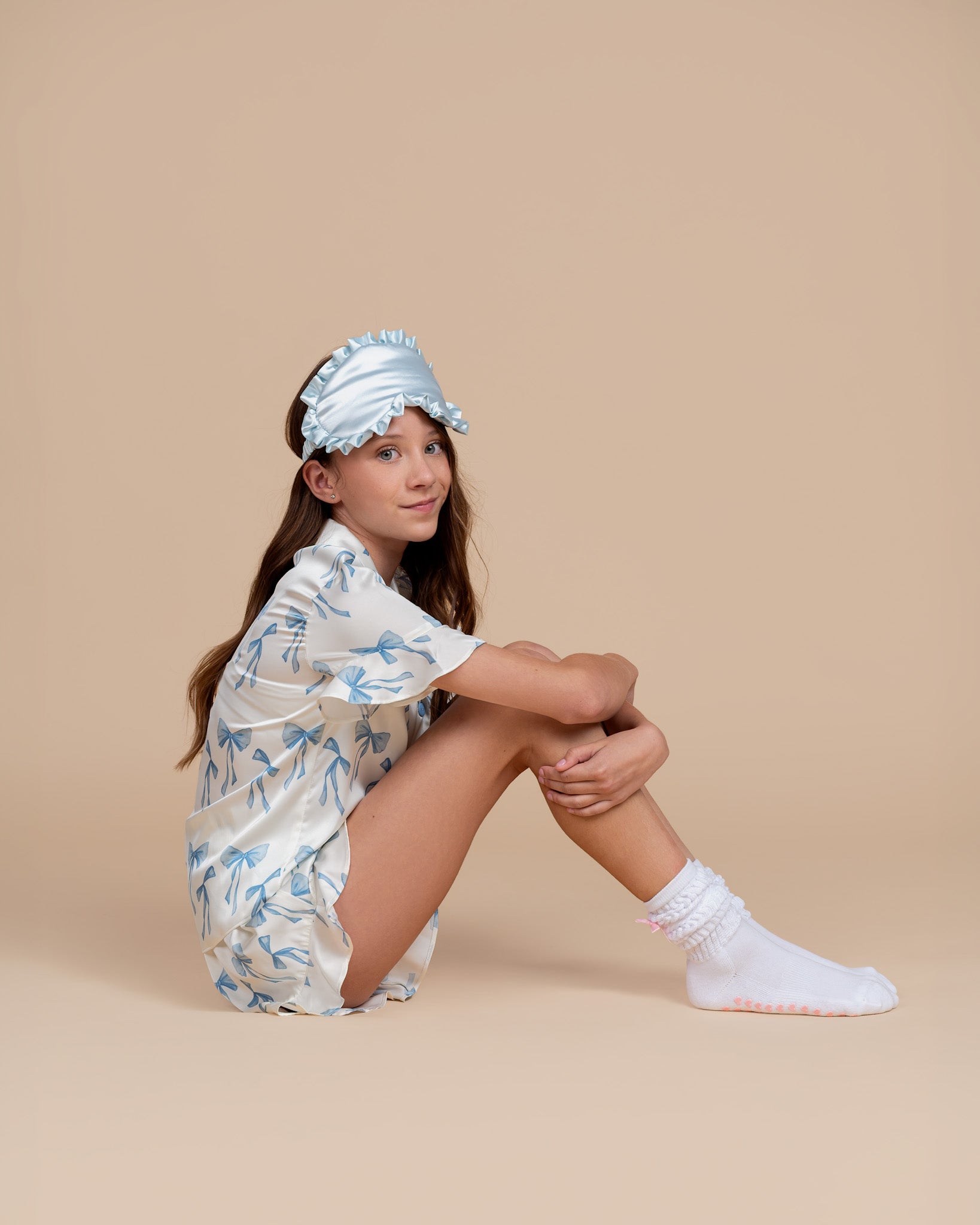 Tween model wearing Dream Queen Co. Chill Queen Ruffle satin PJ set in Coquette Code blue Bow print