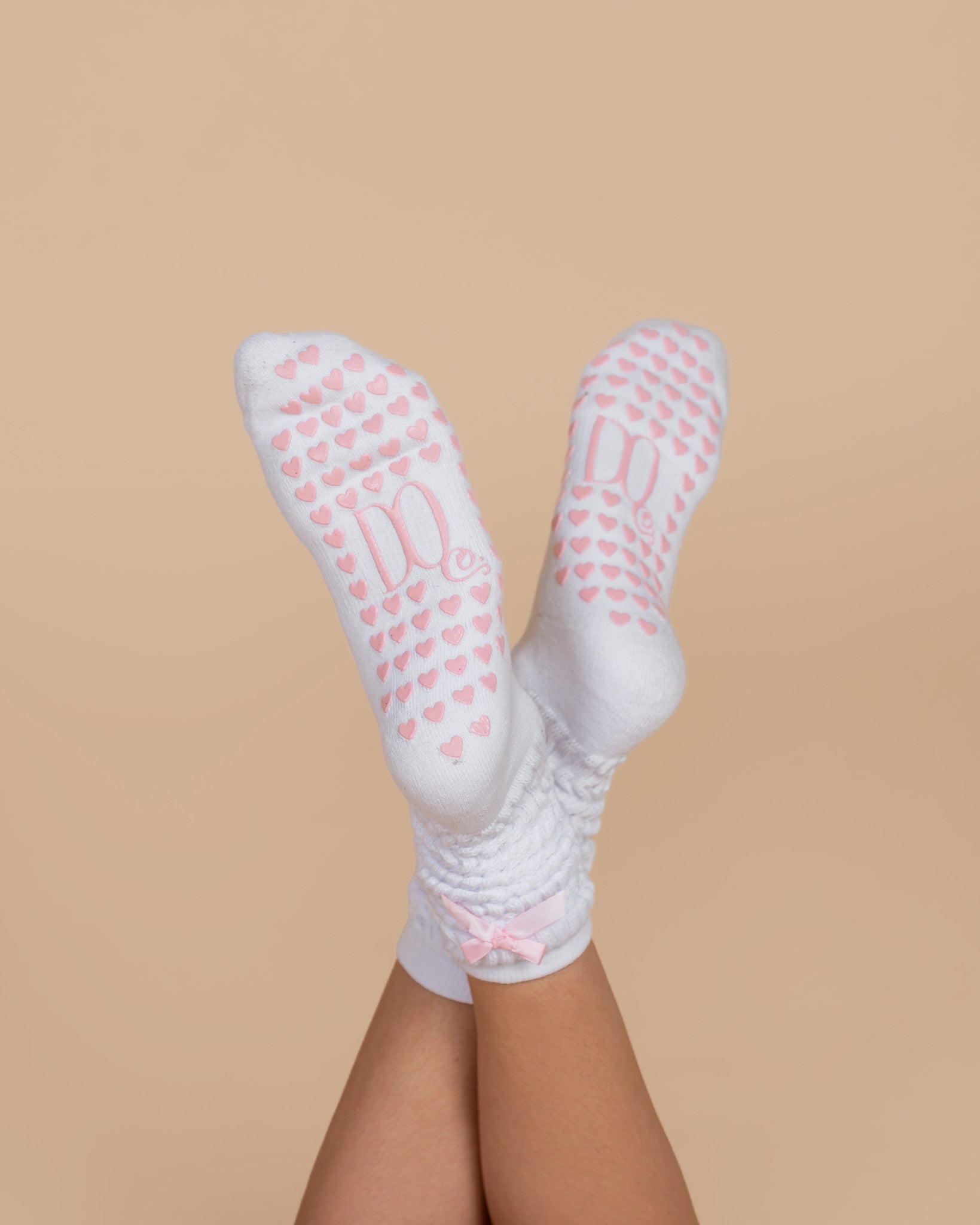 White grip pilates bed socks with pink hearts, logo and pink bow